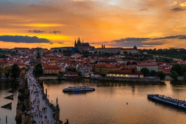 The sun sets on the Prague Castle with the Charles Bridge below.